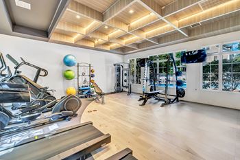 A gym with a variety of exercise equipment including treadmills, stationary bikes, and weight machines.